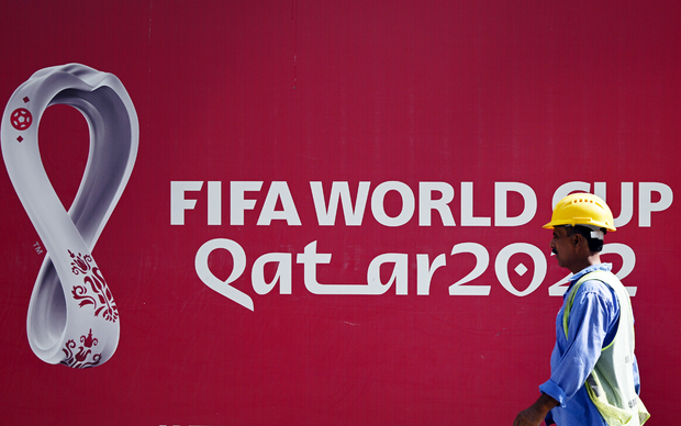 Strani radnik u Dohi prolazi ispred plakata Svjetskog prvenstva (Foto: Federico Gambarini/DPA)